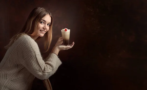 Красивая блондинка в свитере держит кружку кофе со сливками — стоковое фото
