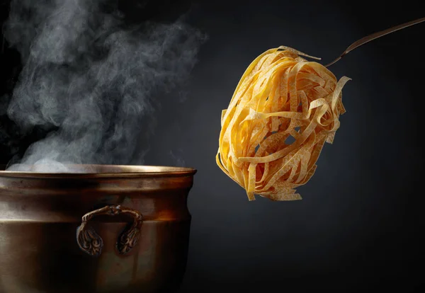 Zelfgemaakte rauwe eiernoedels en oude koperen pan met warm water. — Stockfoto