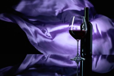 Şarap kadehi ve siyah yansıtıcı backgroun kırmızı şarap şişesi