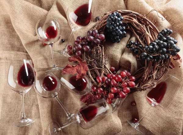 Rotwein und Trauben auf einem mit Kletten bedeckten Tisch. — Stockfoto