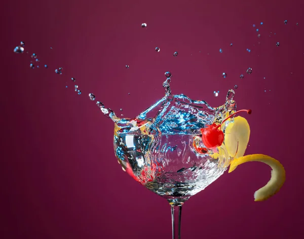 Ccktail in glass with splashes garnished with lemon and cherries — Stock Photo, Image