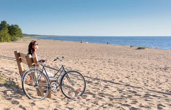 Mujer de mediana edad llegó en una bicicleta a la playa y sentarse a descansar —  Fotos de Stock