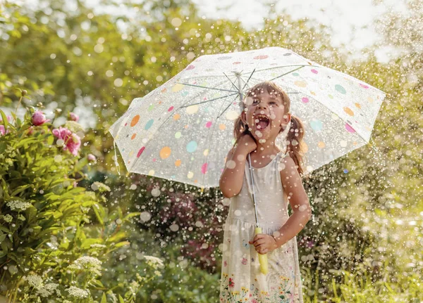 Bonne petite fille dans le jardin sous la pluie d'été avec un umbrel — Photo