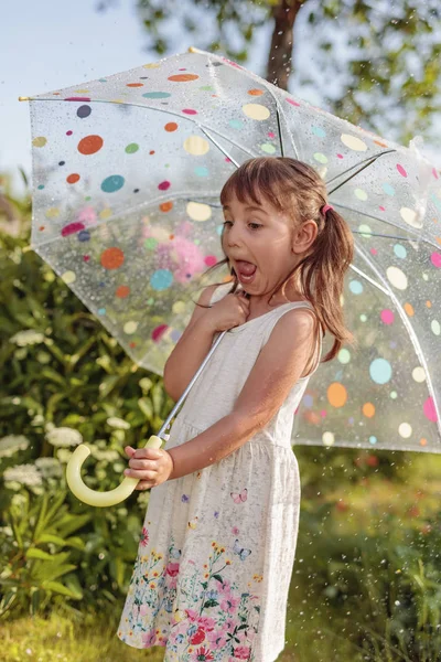 アンブレルと夏の雨の下で庭で幸せな小さな女の子 — ストック写真