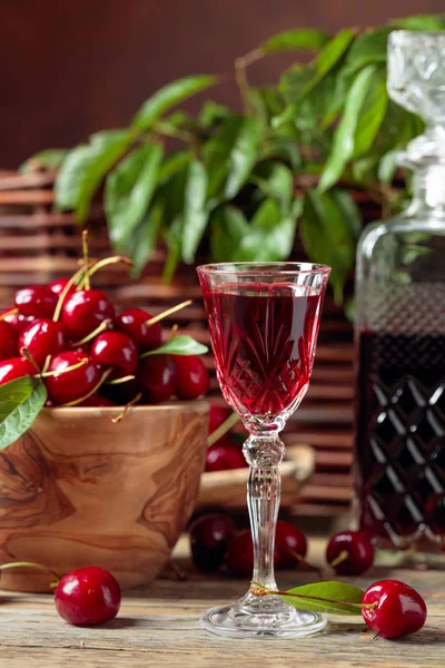Cherry liquor and red cherries in a wooden bowl on a wooden tabl — Stock Photo, Image