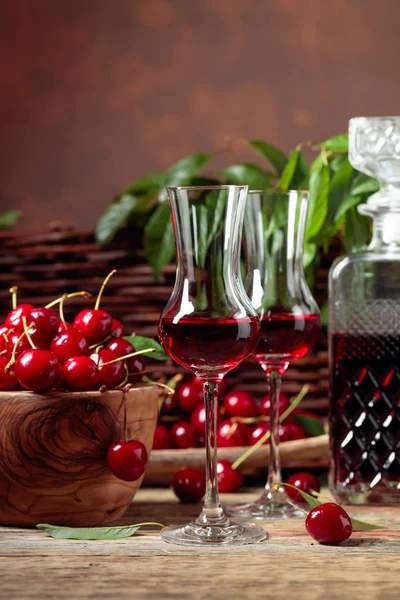 Cherry liquor and red cherries in a wooden bowl on a wooden tabl — Stock Photo, Image