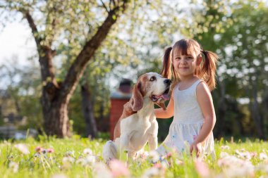 mutlu küçük kız bahçede köpekle oynayan.