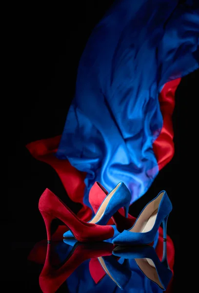 Μπλε και κόκκινα γυναικεία παπούτσια κοτλέ σε ένα μαύρο ανακλαστικό πίσω — Φωτογραφία Αρχείου