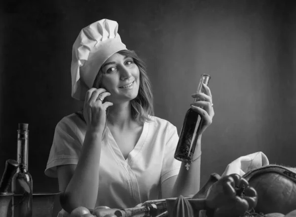 올리브 오일의 작은 병과 요리사 유니폼을 입은 젊은 여성. — 스톡 사진