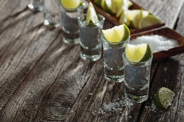 Tequila con sal y lima sobre un fondo de madera viejo . — Foto de Stock