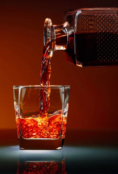 Alkoholhaltiga drycker hälla från en dekanter i ett glas. — Stockfoto