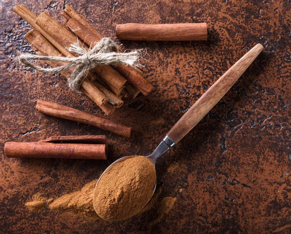 Varas de canela e pó em colher em uma mesa de cobre velha  . — Fotografia de Stock