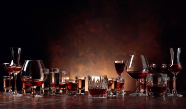 Set of strong alcoholic beverages in glasses on a brown backgrou clipart
