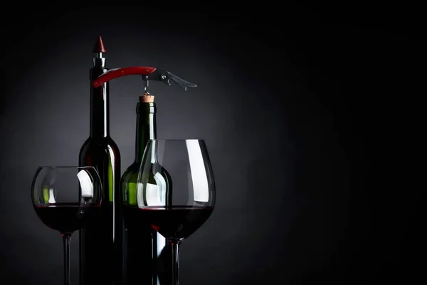 Red wine with corkscrew on a black background. — Stock Photo, Image