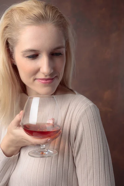 Portret van een mooie vrouw met glas cognac. — Stockfoto