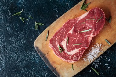 Taze çiğ Dana biftek biberiye ve deniz ile ahşap tahta üzerinde tuz.