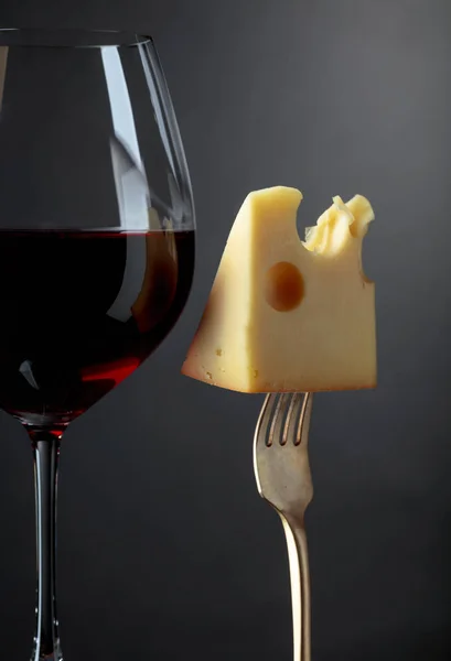 Queijo Maasdam com vinho tinto sobre fundo escuro . — Fotografia de Stock
