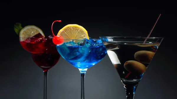 Two colorful cocktails and dry martini with green olives. — Stock Photo, Image