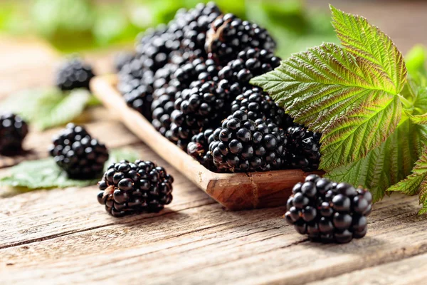 Ripe juicy blackberries with leaves on a wooden table. — Stock Photo, Image