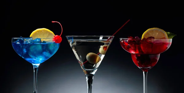 Dva barevné koktejly a suché Martini se zelenými olivami. — Stock fotografie