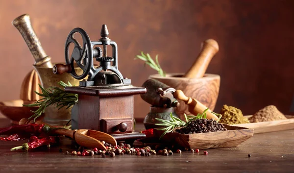 Vintage pepper mill with kitchen utensils, spices and rosemary o — Stock Photo, Image