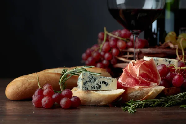 Bread with prosciutto, blue cheese and rosemary on a dark backgr — Stock Photo, Image