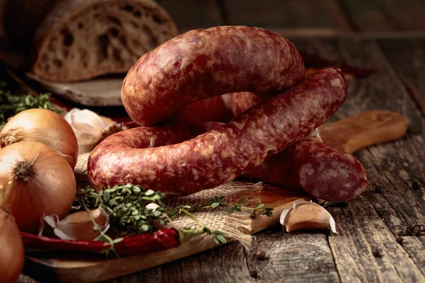 Dry-cured sausage with bread and spices on a old wooden table. — Stock Photo, Image