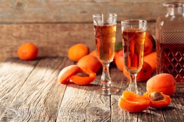 Kayısı likörü ve taze kayısı eski ahşap bir masada.  