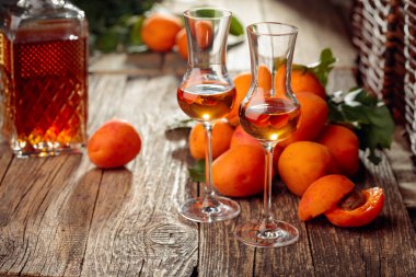 Kayısı likörü ve taze kayısı eski ahşap bir masada.  