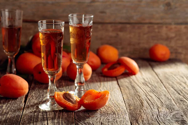 Apricot liquor and fresh apricots on a old wooden table. — Stock Photo, Image
