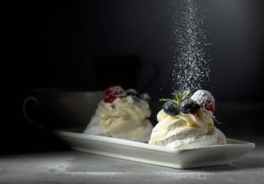 Tatlı Pavlova ile pudra şekeri serpilir.