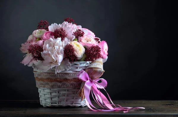 Bouquet de pivoines roses dans un panier blanc avec ruban rose . — Photo