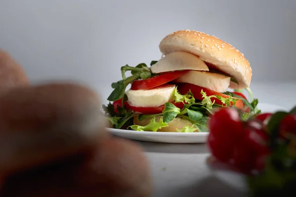 Сэндвич с моцареллой, помидорами и салатом на кухонном столе . — стоковое фото