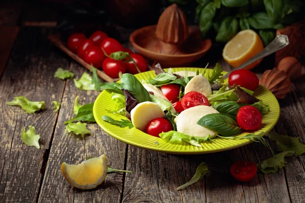 Green salad with mozzarella, tomato and basil in green plate on — Stock Photo, Image