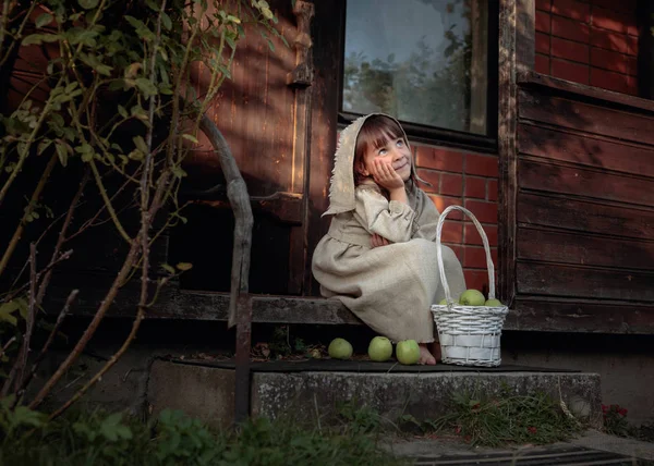 Dreaming girl with apples on a summer evening near the old house — Stock Photo, Image