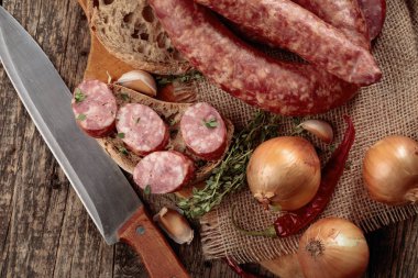 Eski ahşap bir masada ekmek ve baharat ile kuru-tedavi sosis.