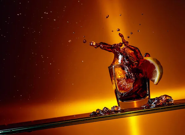 Kawałek cytryny wpadając w szklankę Cola. — Zdjęcie stockowe