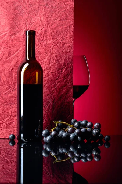Bottle and glass of red wine on a black table. — Stock Photo, Image