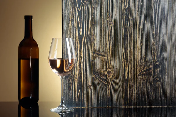 Bottiglia e bicchiere di vino bianco su un tavolo nero. — Foto Stock