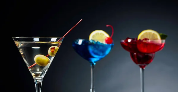 Two colorful cocktails and dry martini with green olives. — Stock Photo, Image