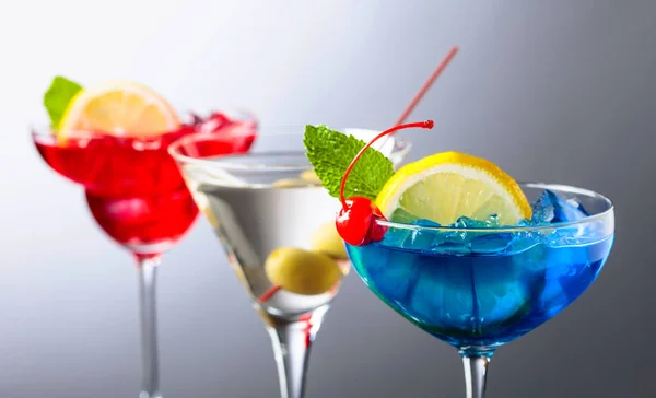Zwei bunte Cocktails und trockene Martini mit grünen Oliven. — Stockfoto