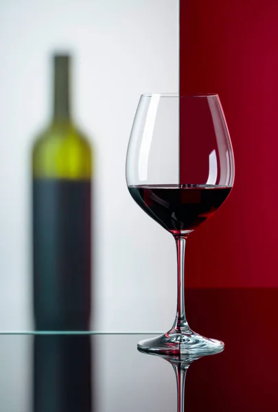 黒い反射の背景に赤ワインのボトルとグラス. — ストック写真