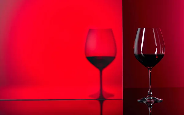 黒い反射の背景に赤ワインのグラス. — ストック写真
