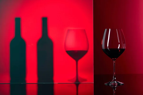 黒い反射の背景に赤ワインのボトルとグラス — ストック写真