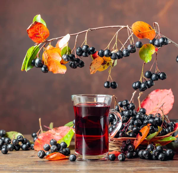 Fresh juice of  black chokeberry in glass and berries with leave — Stock Photo, Image