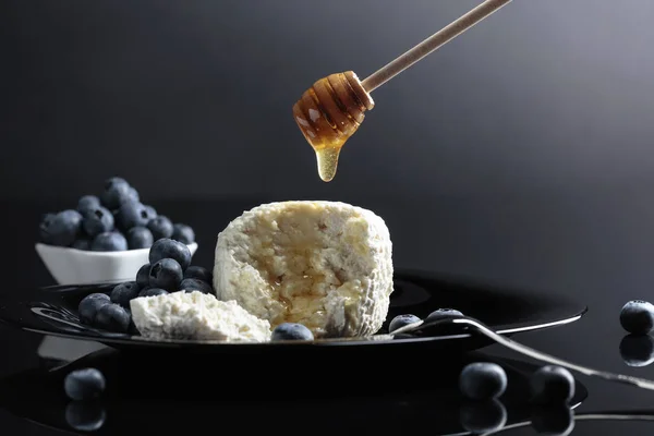 Cottage cheese with honey and blueberry on a black plate. — Stock Photo, Image