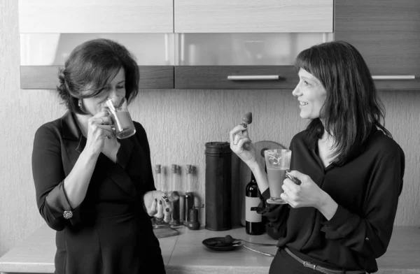 Two girlfriends talk and drink coffee in the kitchen. — Stock Photo, Image