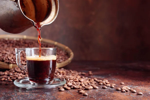 Café negro se vierte en una pequeña taza de vidrio . — Foto de Stock