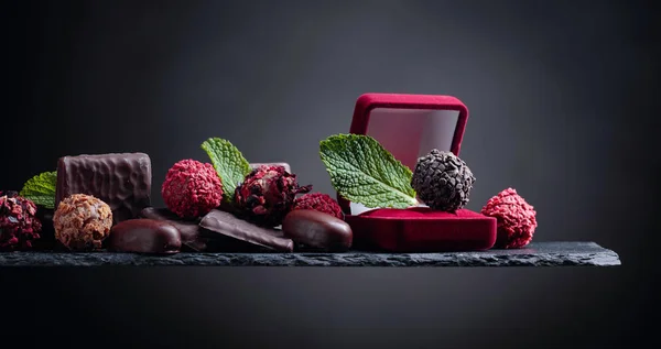 Різні шоколадні цукерки з листя м'яти на чорному тлі . — стокове фото