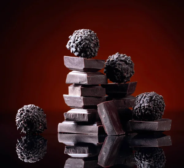 I vari cioccolatini con pezzi di cioccolato rotti sul nero riflettono — Foto Stock